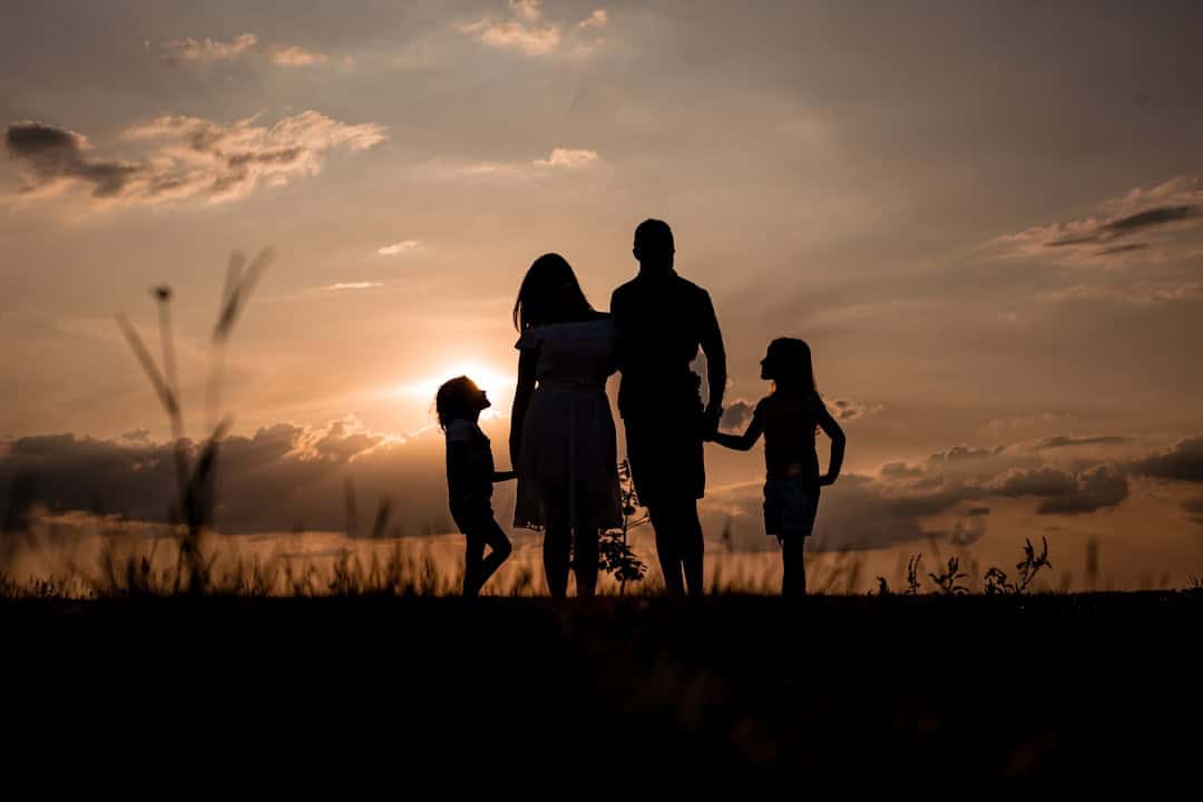Family enjoying sunset outdoors, silhouette image.
