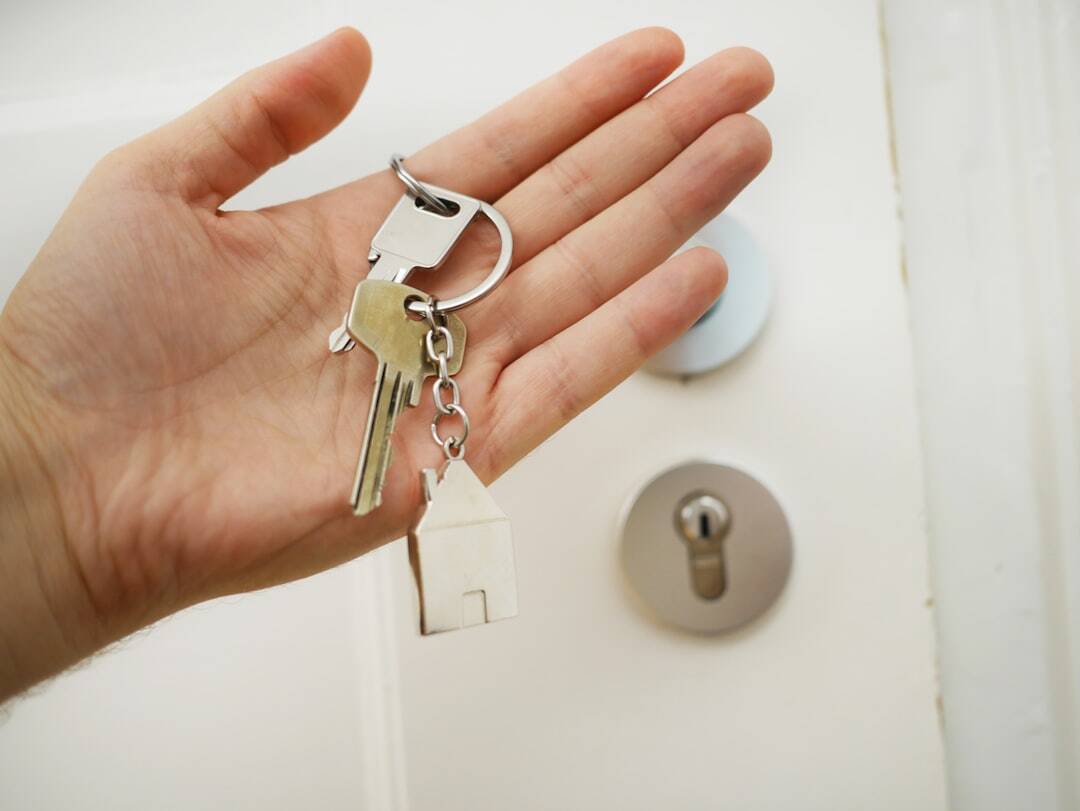 House key on a keychain held in hand near door lock.